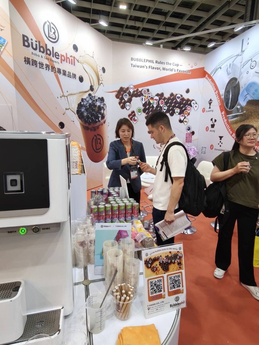 BubblePhil staff meeting an international buyer at the company trade show booth, with a world map of export markets